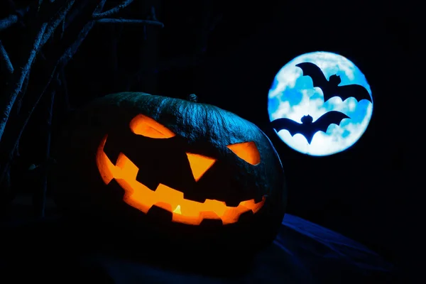 Ijesztő Halloween tök, izzó arcát, és a háttérben a telihold a denevérek — Stock Fotó