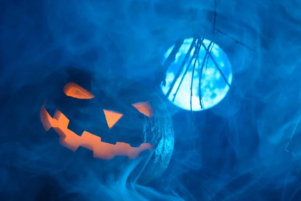 Страшная тыква на Хэллоуин с сияющим лицом на фоне полнолуния в тумане — стоковое фото