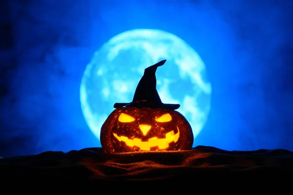 Halloween pumpa i häxa hatt på en bakgrund av fullmånen i dimman — Stockfoto