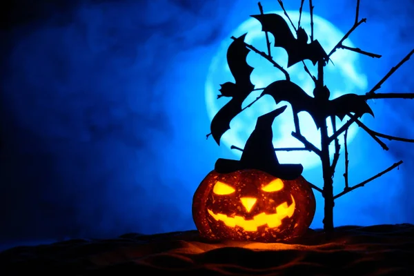 Zucca di Halloween e pipistrelli su un albero, la luna piena nella nebbia dietro — Foto Stock