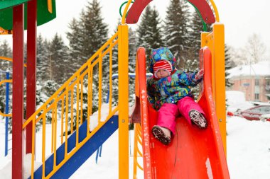 Küçük bir kız bir roller coaster parkta kışın sürme.