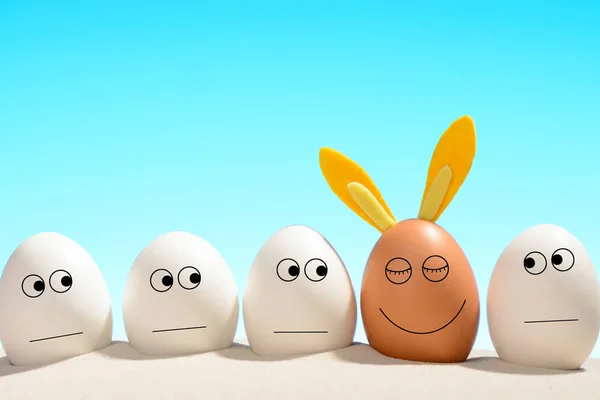 Huevos blancos, mirando al marrón bronceado con orejas de conejo. Pascua en la playa concepto . —  Fotos de Stock