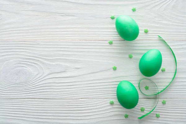 Composition of a green Easter egg with ribbon on wooden background. Top view with copy space