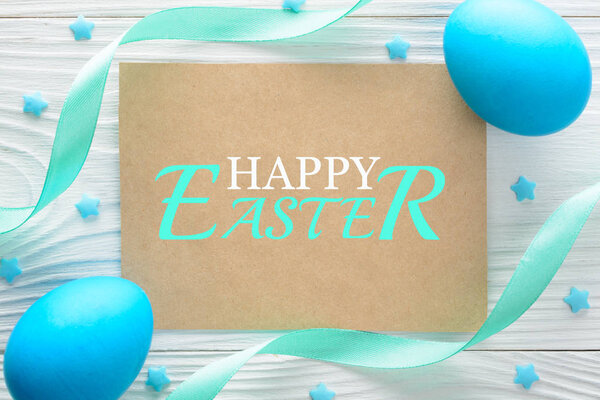 Happy Easter greeting card and colorful eggs on the wooden table. Top view