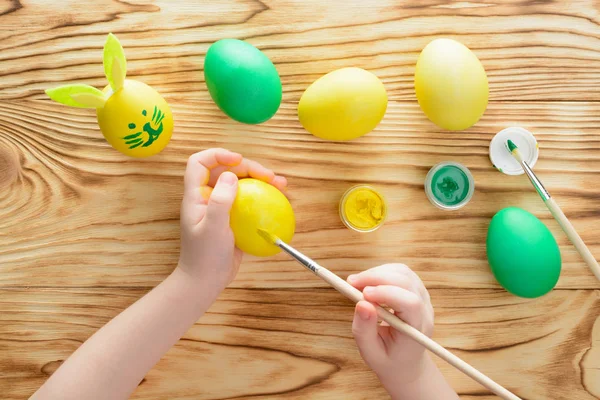 Easter concept. Child hands coloring eggs for Easter. Top view