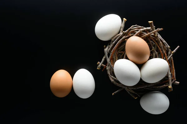 Fondo de Pascua. Los huevos blancos y castaños en el nido de las ramas sobre el fondo negro —  Fotos de Stock