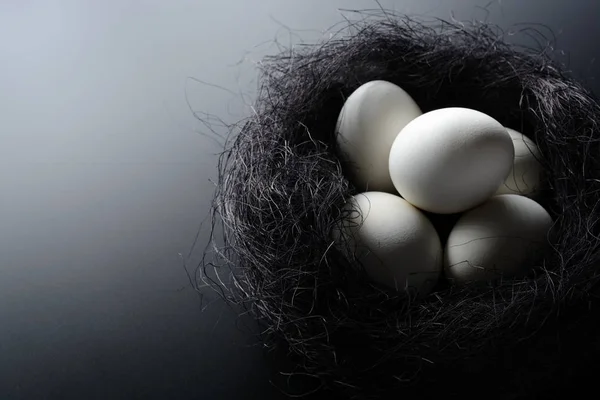Ovos brancos em um ninho de sisal em fundo preto — Fotografia de Stock