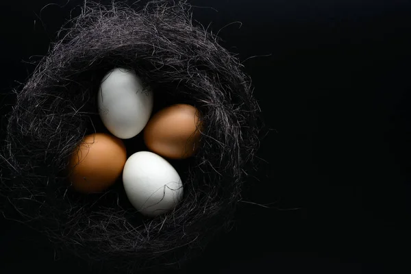 Los huevos blancos y castaños en el nido del sisal sobre el fondo negro —  Fotos de Stock