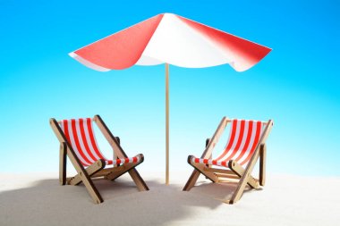 İki şezlong şemsiye kum plajındaki kopya alanı ile gökyüzü altında