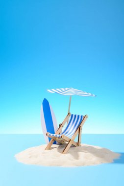 Tatil tropikal kavramı. Bir şezlong altında bir şemsiye ve kumlu ada üzerinde sörf tahtası. Kopya alanı ile gökyüzü