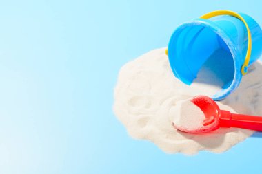 Oyuncak plastik kova ve kürek kum. Kopya alanı ile mavi arka plan