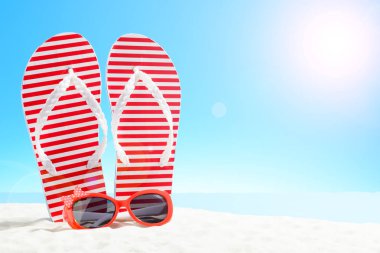 Flip flop ve kumlu plajda güneş gözlüğü kırmızı çizgili