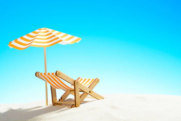 Een chaise longue onder een paraplu aan het zandstrand, de hemel met kopie ruimte — Stockfoto