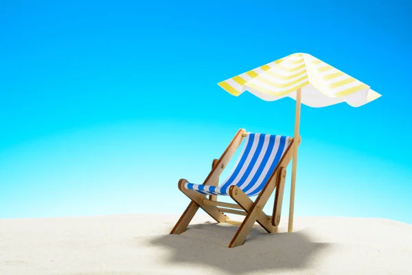 Una chaise longue bajo un paraguas en la playa de arena, cielo con espacio para copiar — Foto de Stock