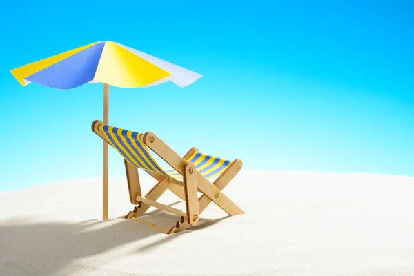 Une chaise longue sous un parapluie sur la plage de sable, ciel avec espace de copie — Photo