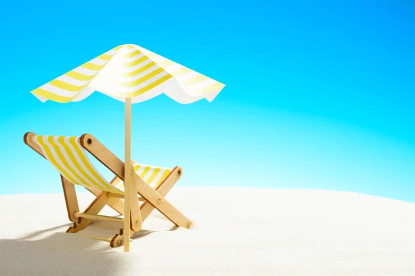 Een chaise longue onder een paraplu aan het zandstrand, de hemel met kopie ruimte — Stockfoto