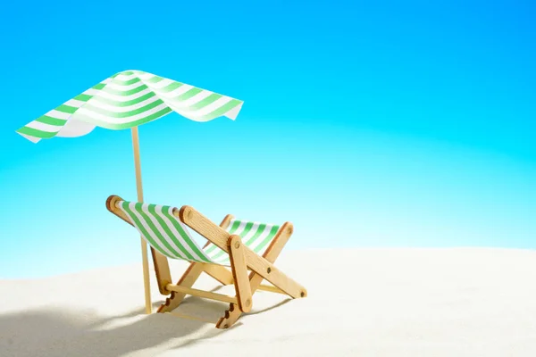 Une chaise longue sous un parapluie sur la plage de sable, ciel avec espace de copie — Photo