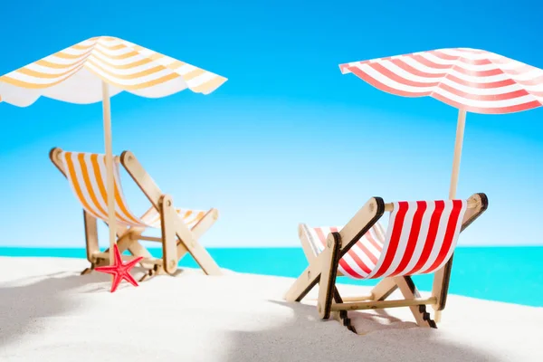 Twee ligstoelen onder een paraplu op het zandstrand aan de zee en de hemel met kopie ruimte — Stockfoto