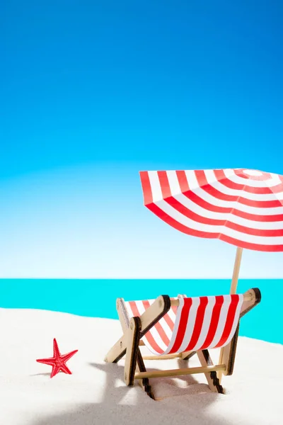 Una chaise longue bajo un paraguas en la playa de arena junto al mar y el cielo con espacio para copiar — Foto de Stock