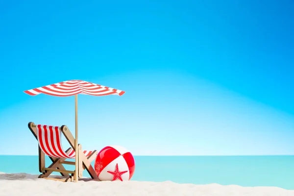 Lounge chair with parasol and beach ball on the coast — Stock Photo, Image