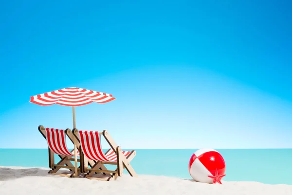 Due sedie a sdraio con ombrellone e beach ball sulla costa — Foto Stock