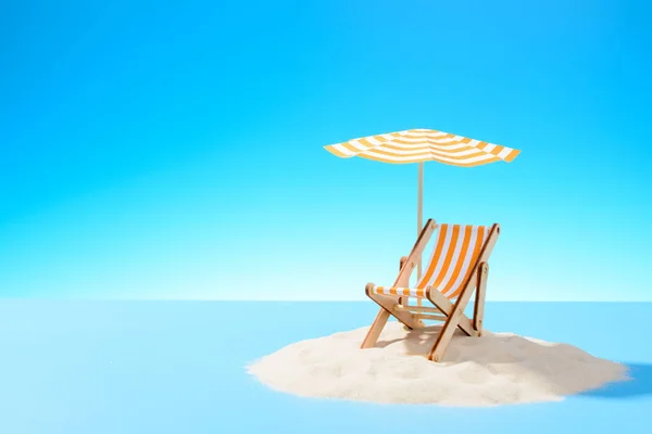 El concepto de unas vacaciones tropicales. Una chaise longue bajo un paraguas en la isla de arena. Cielo con espacio de copia —  Fotos de Stock