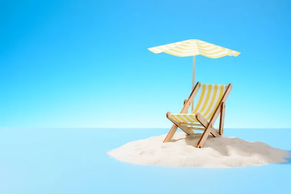 El concepto de unas vacaciones tropicales. Una chaise longue bajo un paraguas en la isla de arena. Cielo con espacio de copia — Foto de Stock