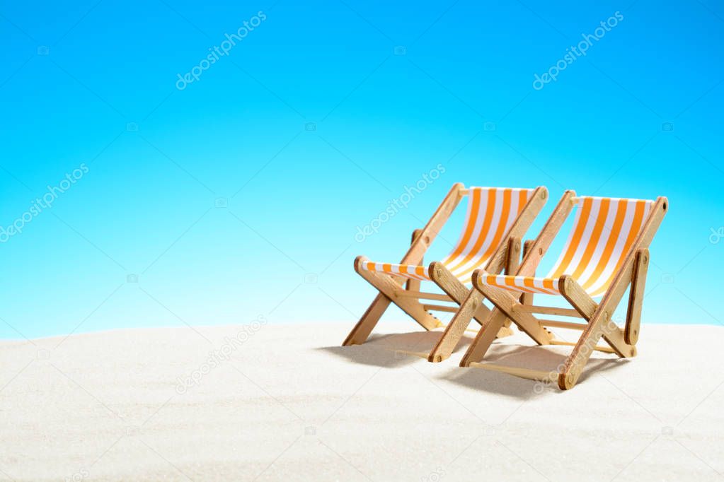 Two sun loungers on the sandy beach and the sky with copy space