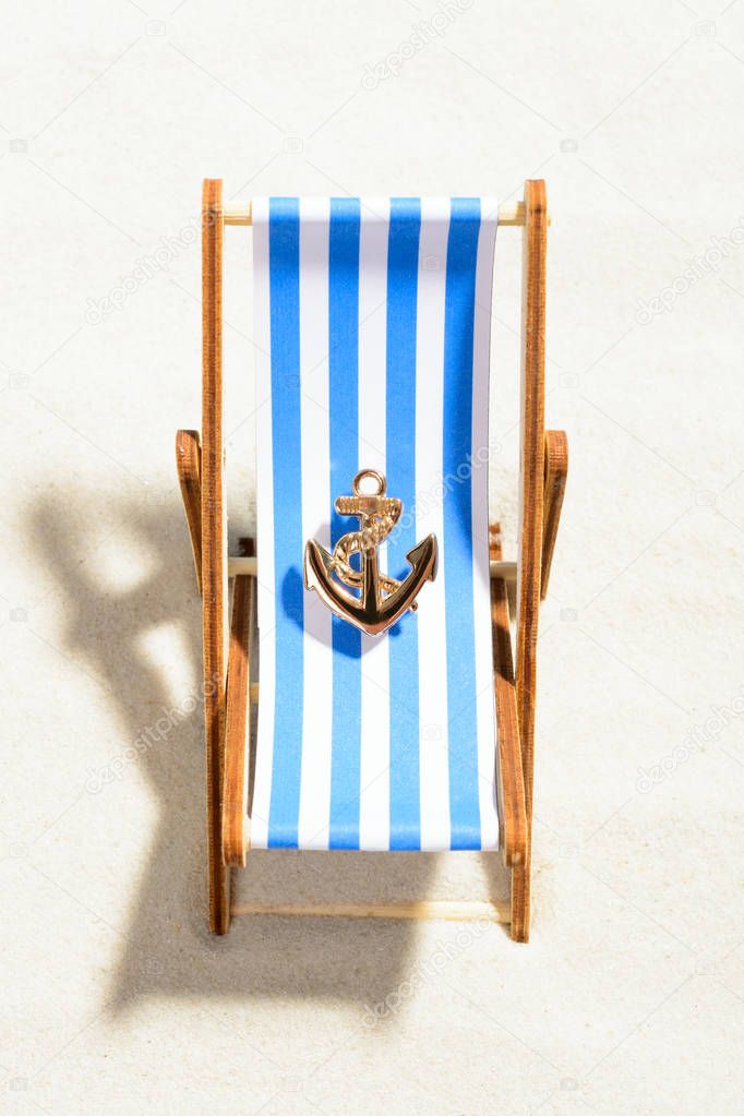 Miniature anchor on a striped chaise longue