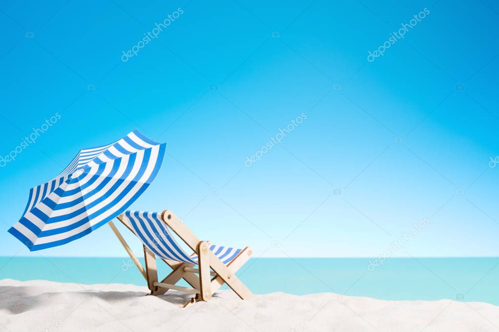 A chaise longue under an umbrella on the sandy beach by the sea