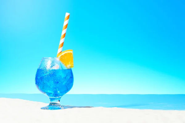 Erfrischendes blaues Getränk mit Eis und einer Orangenscheibe im Glas an der Sandküste — Stockfoto