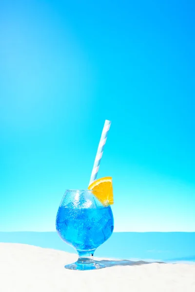 Erfrischendes blaues Getränk mit Eis und einer Orangenscheibe im Glas an der Sandküste — Stockfoto