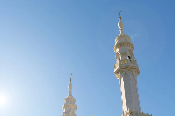 Two white minarets against the blue sky. Copy space, sun rays — Stock Photo, Image
