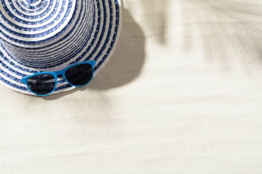 Şapka üstten görünüm ile kum ve mavi güneş gözlüğü üzerinde