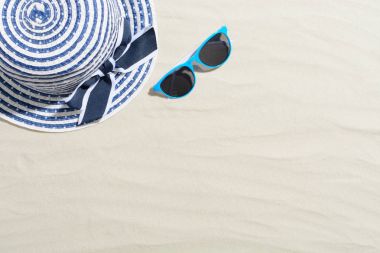 Şapka üstten görünüm ile kum ve mavi güneş gözlüğü üzerinde