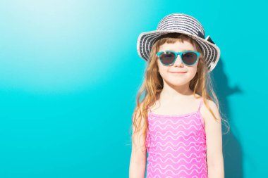 Plaj kıyafeti mavi arka plan üzerinde büyüleyici küçük kız