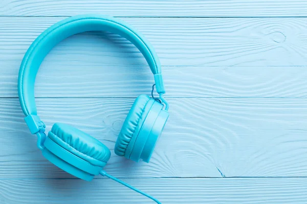 Large blue earphones on wooden background from above