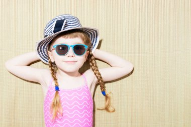 Yukarıdan bir güneş gözlüğü ve plaj şapka ile yalan mayo mutlu küçük kız