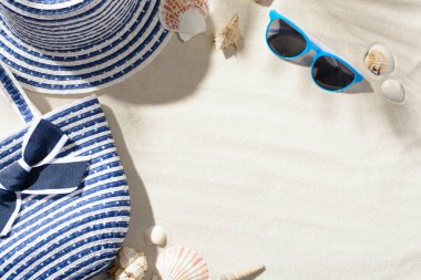 Deniz kabuklarını kum üzerinde plaj şapka, güneş gözlüğü ve çanta arasındadır