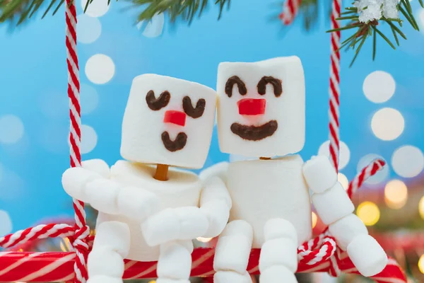Deux amoureux des bonhommes de neige de guimauve sont assis sur une balançoire de bonbons. Noël rencontre un couple amoureux concept . — Photo