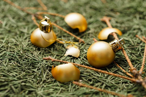 Сломанные золотые рождественские шары на упавших сухих иглах елки с ветками . — стоковое фото
