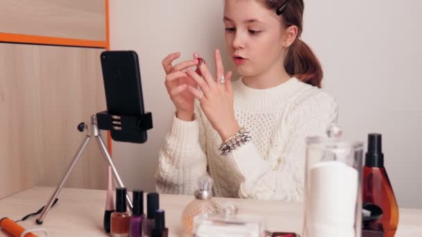 Κομψό νεαρή blogger κορίτσι δείχνει τα κοσμήματά της στους συνδρομητές. Σου μαθαίνει να είσαι στιλάτος. Καταγράφει βίντεο για ένα blog σε κοινωνικά δίκτυα χρησιμοποιώντας μια κάμερα smartphone σε τρίποδο. — Αρχείο Βίντεο