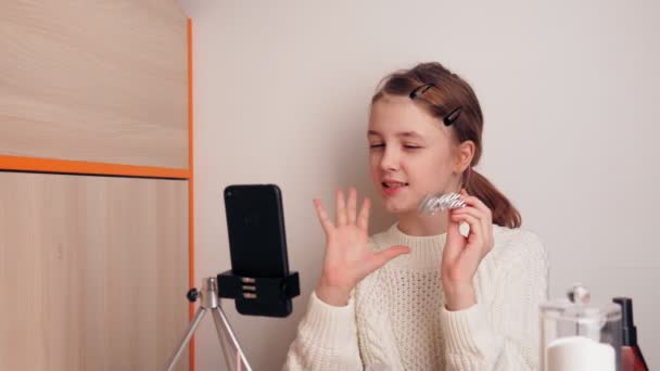 Élégant jeune fille blogueur montre ses bijoux aux abonnés. Ça t'apprend à être élégant. Enregistre une vidéo pour un blog sur les réseaux sociaux à l'aide d'une caméra smartphone sur un trépied . — Video