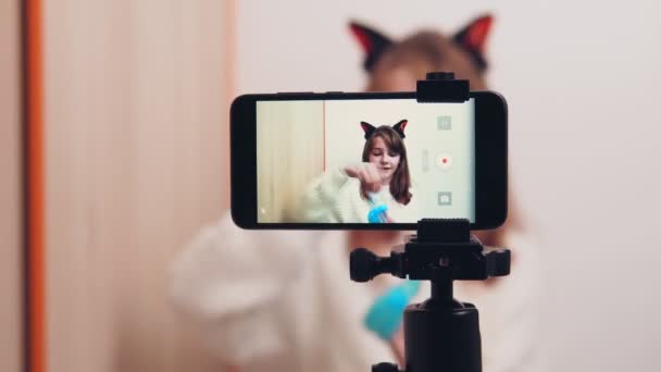 Leuk gelukkig meisje gebruikt een smartphone voor een video blog op sociale netwerken. Een meisje blogger shows en praat op de telefoon camera over een speelgoed slijm. — Stockvideo