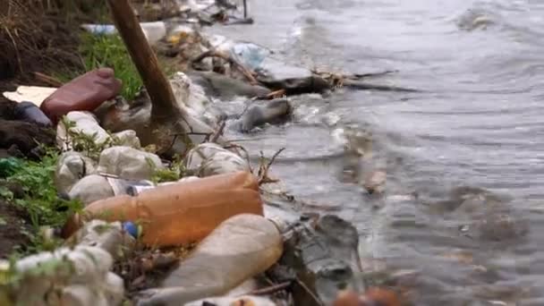 Inquinamento plastico dell'ambiente. Bottiglie di plastica e altri rifiuti non degradabili sulla costa di uno stagno. — Video Stock