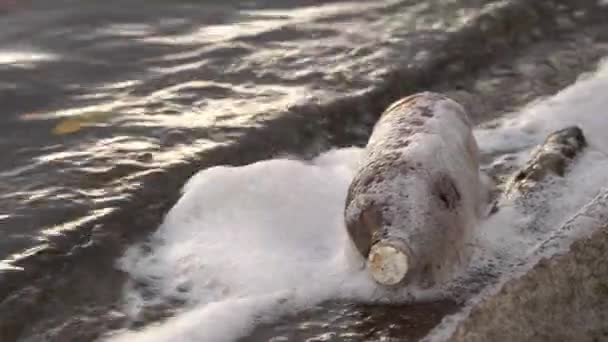 Contamination plastique du milieu aquatique. Gros plan d'une bouteille en plastique balançant sur les vagues au large d'un réservoir . — Video