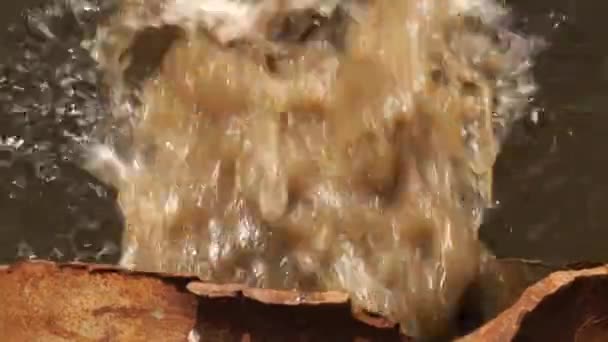 Water pollution. Wastewater is discharged through a rusty sewer into a body of water. — Stockvideo