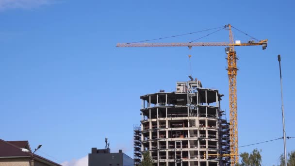Turmdrehkran und monolithisches Betongebäude vor blauem Himmel. Bau eines Hochhauses, 4k. — Stockvideo