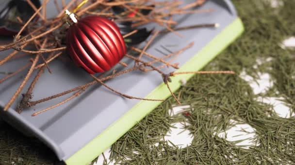 Ένα κοντινό πλάνο με σπασμένα Χριστουγεννιάτικα μπαλάκια και ξερά κλαδιά πεύκου σε γκρι σέσουλα σε ένα τραπέζι με πεσμένες πευκοβελόνες.. — Αρχείο Βίντεο