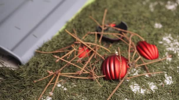 Detailní záběr, muž sbírá rozbité vánoční míče a suché borové větve s padlými borovicovými jehlicemi z podlahy pomocí šedého kopečku a zeleného štětce. — Stock video